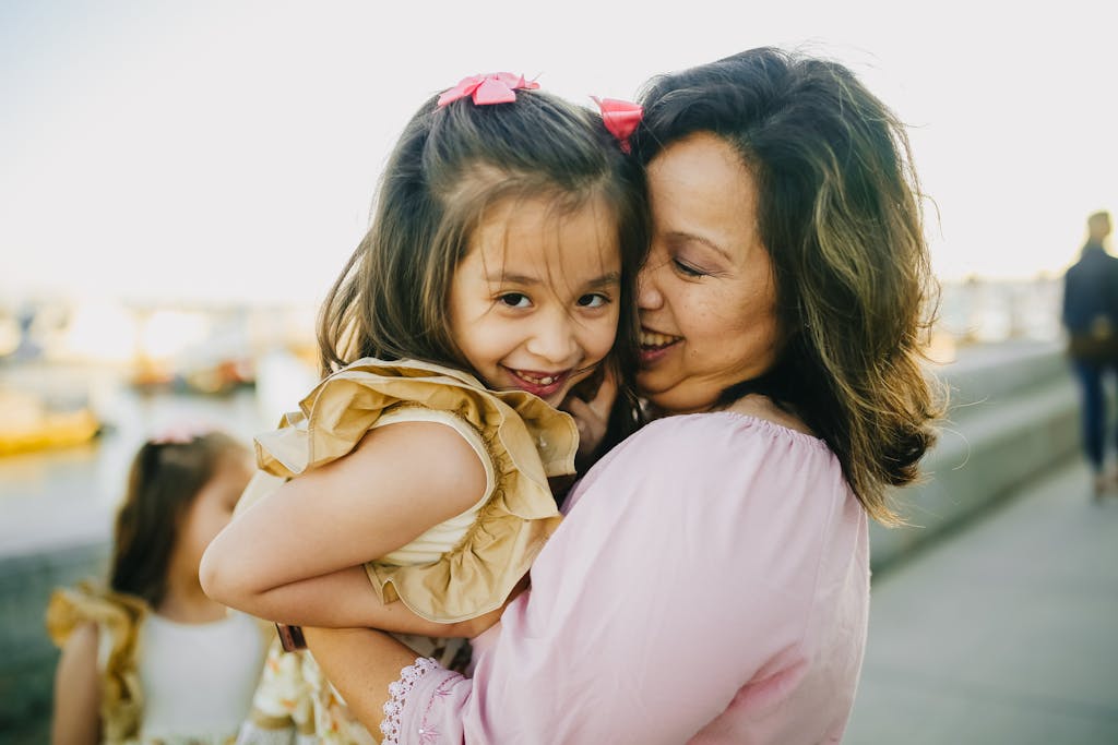 A joyful moment of a mother embracing her daughter outdoors, capturing love and happiness.